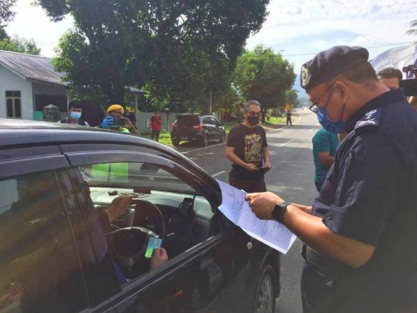 Shafien memeriksa surat yang dikemukakan oleh orang ramai ketika melalui SJR di Bukit Yong, Pasir Puteh pada Jumaat.