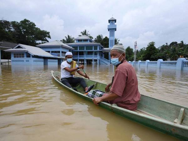 Penduduk Kampung Aceh Mohd Rashik Ujang, 57, dan Mohamad Naziri Razali, 48, mendayung sampan ketika meninggalkan pekarangan masjid selepas menunaikan solat Jumaat ketika tinjauan hari ini.