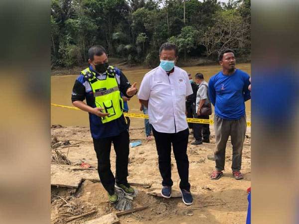 Azli (kiri) bersama Abdul Rahman ketika meninjau tempat penemuan sebuah kapal lama yang dipercayai berusia ratusan tahun terdampar selepas banjir besar di daerah itu surut.
