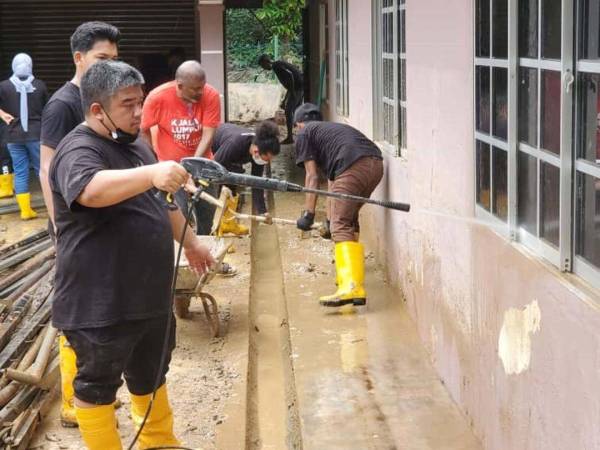 Salah seorang sukarelawan sedang membersihkan bahagian dinding yang kotor akibat pasca banjir.