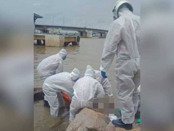 Anggota bomba mengangkat mayat yang ditemukan di tebing sungai Endau berhampiran Jeti LKIM, Mersing pada Ahad.