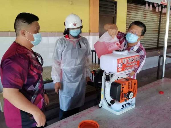 Kok Yew (kanan) membantu menyediakan cecair pembasmi sebelum proses sanitasi bermula.