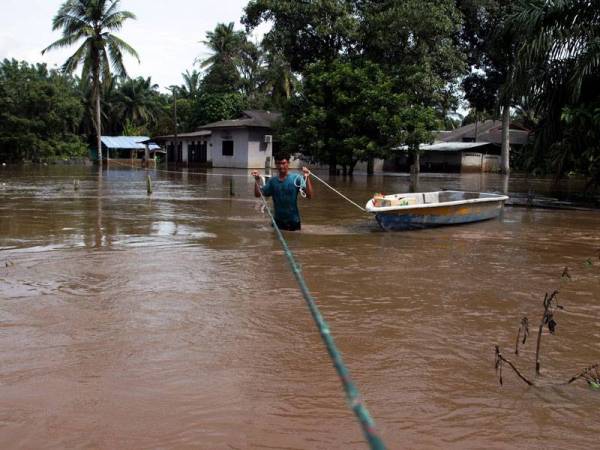 Seorang penduduk Kampung Semangat, Heri Herman Mohd Salim, 35, mengambil langkah berjaga-jaga dengan menggunakan tali yang diikat pada pokok bagi membantunya meredah banjir untuk pulang hari ini melihat keadaan rumah yang lama ditinggalkan. - Foto Bernama
