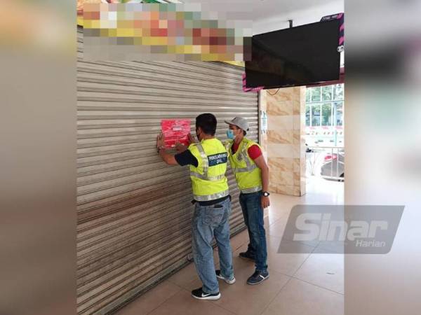 Pegawai penguat kuasa menampal notis penutupan premis yang terletak di Taman Pertama Cheras, Kuala Lumpur pada Isnin.