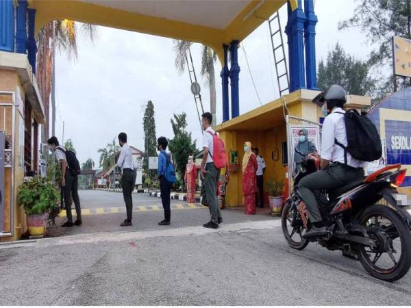Pelajar SMK Dato Razali Ismail melakukan pemeriksaan suhu badan sebelum memasuki kawasan sekolah pada Rabu.