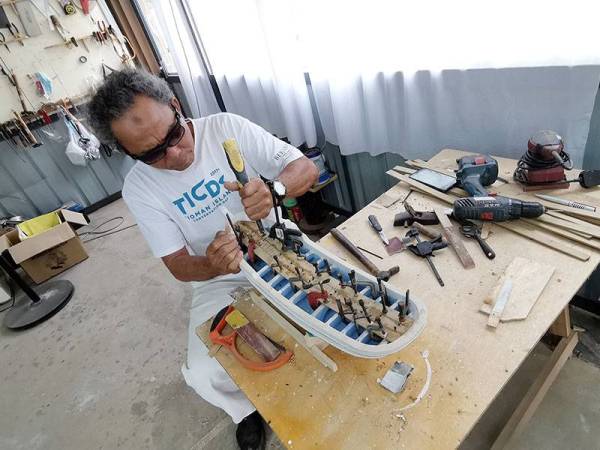 Wan Nordin sedang menyiapkan tempahan sebuah replika perahu daripada jenis pinis yang ditempah pelanggan.