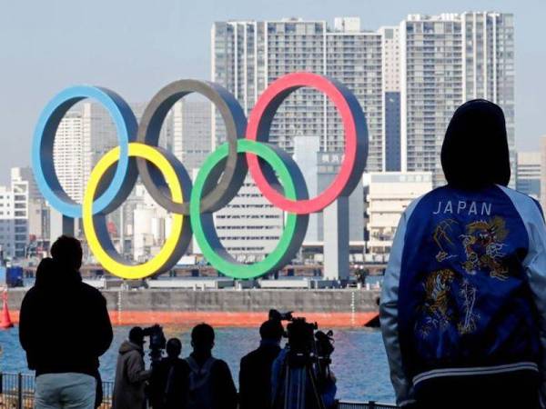 Orang ramai melihat arca Olimpik gergasi dipasang semula di kawasan perairan di Taman Laut Odaiba selepas diturunkan pada Ogos lalu kerana pandemik Covid-19. - Foto Reuters