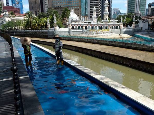 Dua pekerja Dewan Bandaraya Kuala Lumpur (DBKL) membersihkan kolam ikan berhampiran Masjid Jamek yang kelihatan lengang tanpa pelancong susulan pelaksanaan semula Perintah Kawalan Pergerakan (PKP).