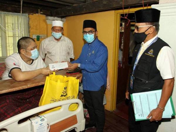 Mohd Firdaus (dua dari kanan) menyampaikan sumbangan wang tunai dan barangan keperluan harian kepada Mohd Saifuddin yang kini tidak dapat bekerja kerana kedua-dua kakinya kudung di Kampung Baru, Johor Bahru pada Isnin.