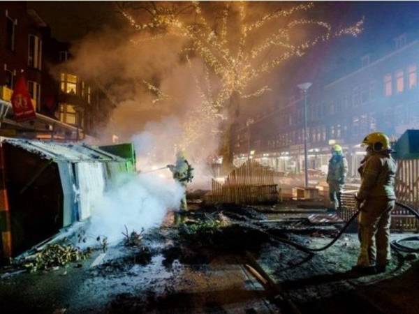 Beberapa anggota bomba berjaya memadamkan api yang berpunca daripada para penunjuk perasaan yang menentang pelaksanaan perintah berkurung di Rotterdam pada Isnin. - Foto AFP