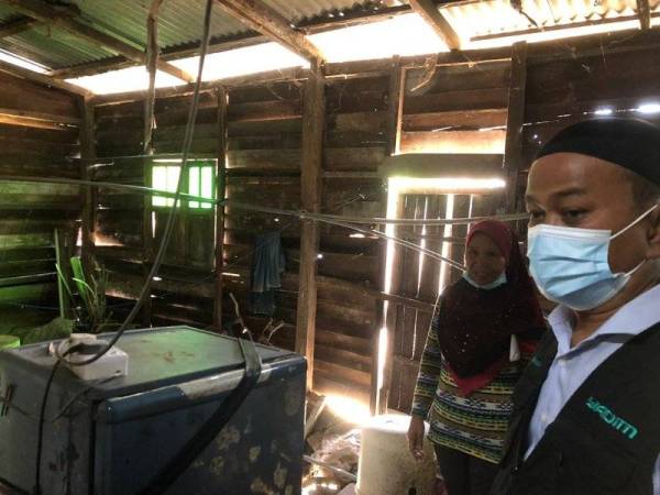 Mahadi Awang (kanan) melihat keadaan dapur rumah yang akan dicadangkan untuk diganti dengan baharu.