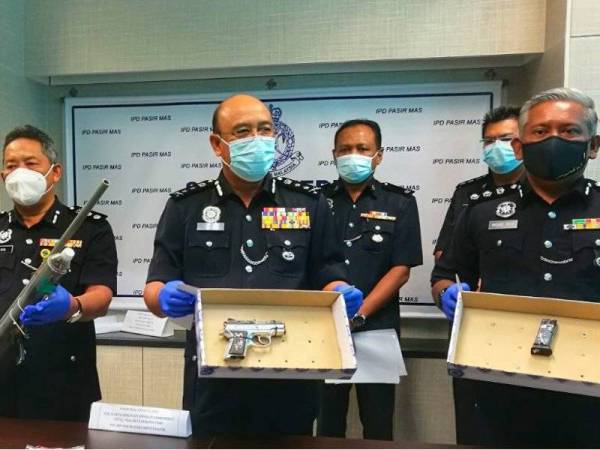 Mohamad Roy Suhaimi (kanan) dan Shafien serta pegawai yang terlibat menunjukkan senjata api yang dirampas berserta peluru semasa sidang media di IPD Pasir Mas.