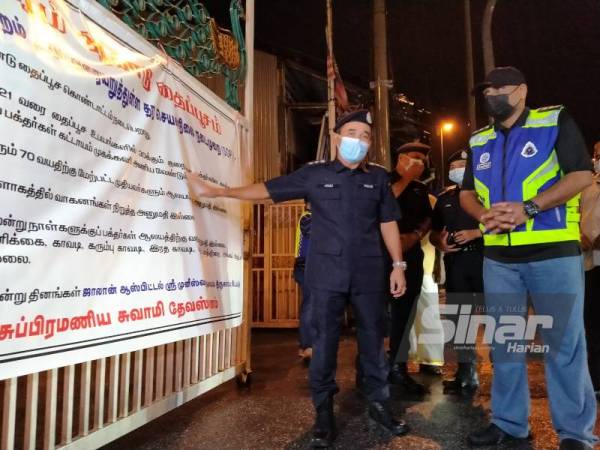 Adzli (kiri) menunjukkan notis penutupan di pintu pagar Kuil Sri Subramaniya Swami Devasthanam Sungai Petani yang merupakan lokasi sambutan Thaipusam ketiga terbesar di Malaysia.