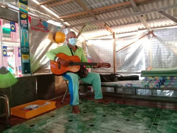 Whasis (kiri) menghiburkan Mohd Fadel dengan memetik gitar ketika melawatnya di pondok di Kampung Paya Dalam, pekan Layang-Layang, Kluang, pada Khamis.
