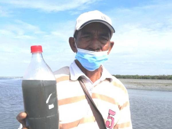 Seorang penduduk menunjukkan sampel air sungai itu berubah warna kehitaman.