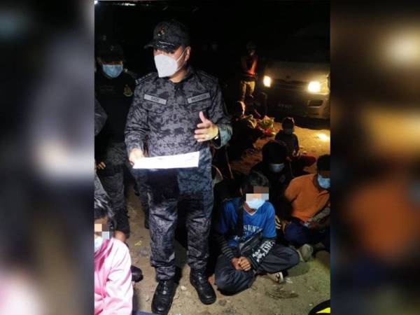 Muhamad Sade (tengah) menjalankan pemeriksaan dalam operasi bersepadu di kawasan rumah setinggan warga asing di Taman Bunga Sulaman, Kota Kinabalu pada Selasa.