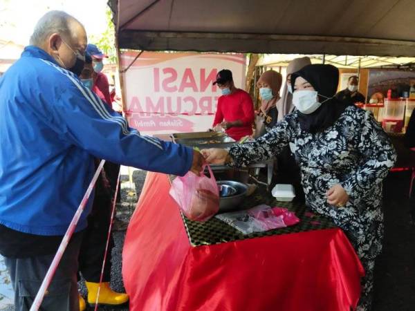 Aja menghulurkan bungkusan nasi percuma kepada orang ramai yang datang ke kedainya di Bukit Setongkol di sini.