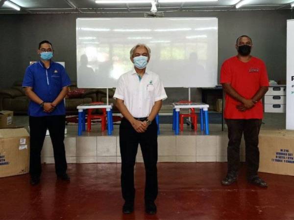 Sazli (tengah) diiringi Hairul Hamid menyampaikan sumbangan kepada Ketua Kampung Sepakat Baru, Azmi Basiran (kanan) untuk diagihkan kepada mangsa-mangsa banjir di Kampung Sepakat Baru, Skudai, Johor Bahru.