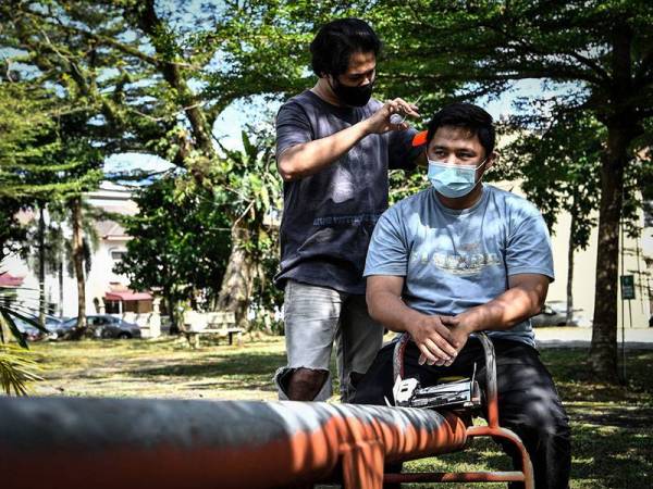 Seorang penjawat awam, Mohd Shahrill Basri, 26, memotong rambut rakan serumahnya Adam Amir Hamzah, 27, di taman perumahan mereka memandangkan tiada kedai perkhidmatan gunting rambut dibuka ketika tinjauan Perintah Kawalan Pergerakan (PKP) hari ini.