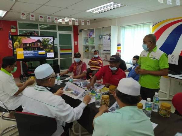 Razman (duduk, dua dari kanan) mendengar taklimat mengenai Model dan Inisiatif Baharu Ekonomi Komuniti (MIBEK) oleh Pengerusi Eksekutif IGROW, Nordin Abdul Malek (berdiri) di Pusat Internet Komuniti Simpang 4 Rungkup, Bagan Datuk pada Ahad.