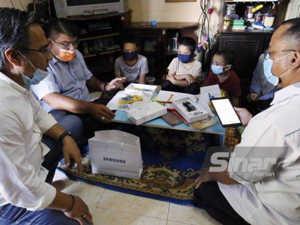 Syed Mohd Johan Rizal (dua dari kiri) menyerahkan sumbangan dua tablet kepada anak-anak Zulhashimi di rumah mereka di Kampung Hujung Mergong, Alor Setar pada Isnin.