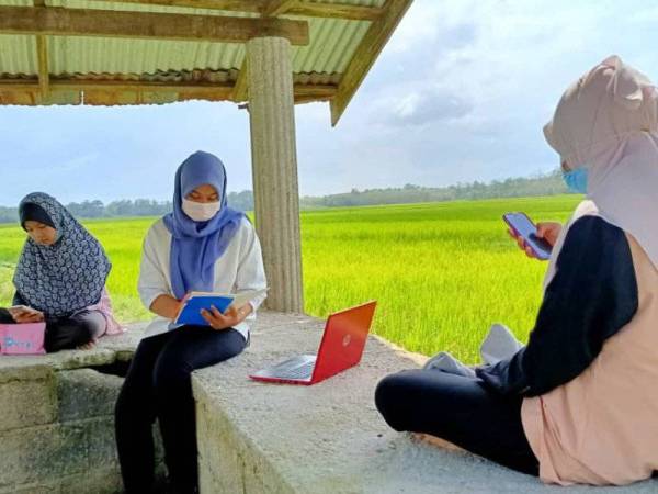 Fathina Uzma (tengah) bersama adik-adiknya mengikuti PdPR di sebuah wakaf di kawasan sawah padi Kampung Kuar kerana capaian internet di kawasan itu kuat berbanding di kampung mereka.