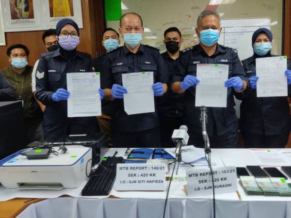 Imran (depan, kanan) menunjukkan antara rampasan slip saringan ujian Covid-19 palsu yang dirampas polis pada Januari lalu.