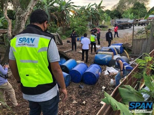 Anggota penguat kuasa SPAN memeriksa tong yang ditemui berisi bahan sisa berjadual di tepi Sungai Langat berhampiran Taman Sri Reko, Cyberjaya malam Selasa.