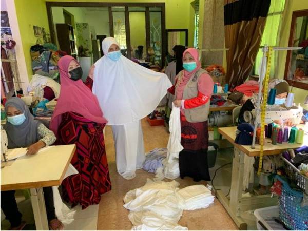 Dr Martina (kanan) dan Rahimah (kiri) melihat telekung solat yang sudah siap dijahit untuk kegunaan pesakit Covid-19.