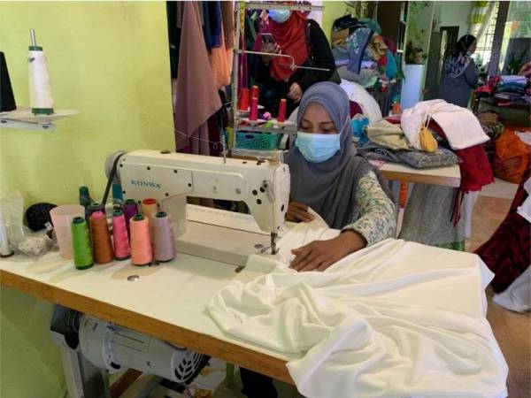 Seorang ibu tunggal, Wan Aziati Wan Mohd Fairuni,41, menjahit telekung solat di Butik V Soho dengan kemas untuk diberikan kepada pesakit Covid-19 di PKRC secara percuma.