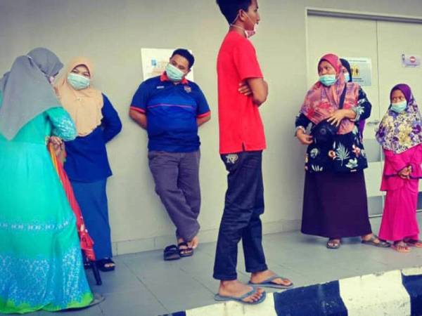 Nurul Syafiqah (kanan) tidak berganjak di hadapan pintu masuk Unit Forensik Hospital Sultan Ismail Petra, Kuala Krai menunggu jenazah ibu bapanya sebelum diarahkan pulang ke rumah. Foto: Ihsan keluarga mangsa