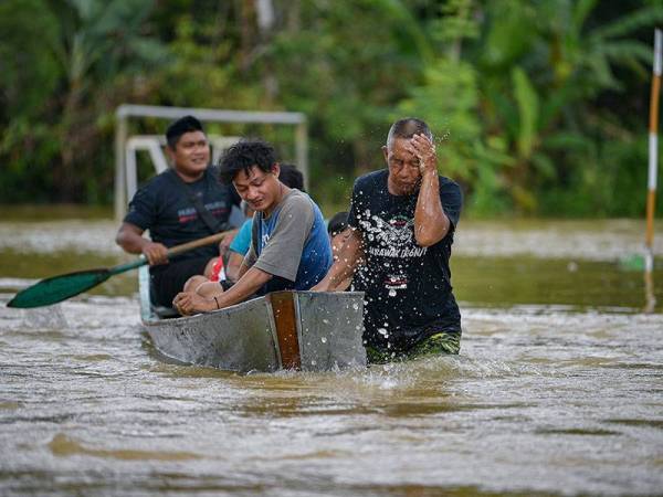 Penduduk Kampung Sorak Melayu, Tebakang, kelihatan meredah air untuk berpindah ke pusat pemindahan sementara (PPS) selepas Kampung itu dilanda banjir, hari ini.