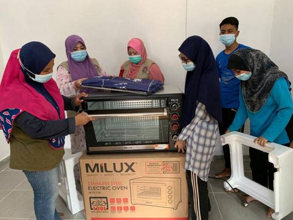 Che Norhayati (dua dari kiri) dan Dr Martina (tiga dari kiri) melihat ketuhar baharu yang diterima oleh Aimi Nazerah (kiri) untuk membantunya berniaga secara kecil-kecilan.