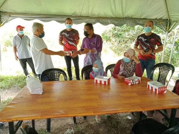 Sabri (kiri) turut menyumbangkan makanan untuk pelajar yang mengikuti PdPR di khemah sementara yang dipasang di Kampung Payong, Setiu.