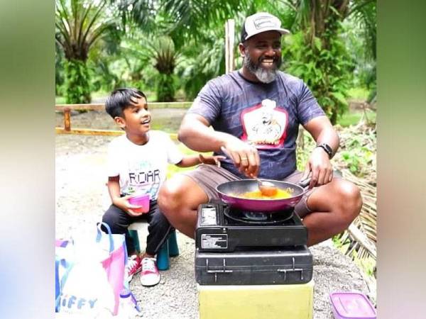 Selvakumar memasak berlatar belakang ladang kelapa sawit bersama anak sulungnya Varma.