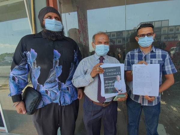 Thanenthiran (tengah) menunjukkan buku yang ditulis Tommy serta laporan polis di Balai Polis Butterworth pada petang Jumaat.