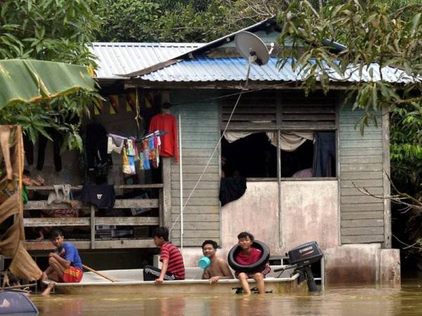 Penduduk kampung mengharungi banjir dengan menggunakan sampan di Kampung Hulu Serian yang ditenggelami air sehingga setinggi kira-kira tiga meter sejak Rabu malam. FOTO: BERNAMA