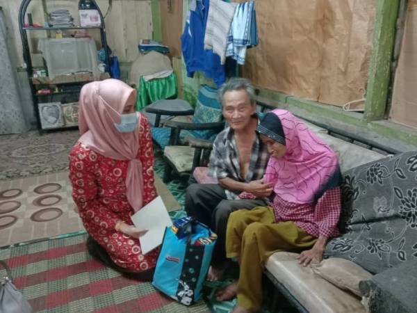 Zainani (kiri) serah sumbangan kepada Arshad dan Saadiah dalam program Ziarah Kasih YPK di kediamannya di Kampung Sembrong Lapis, Kluang pada Jumaat.