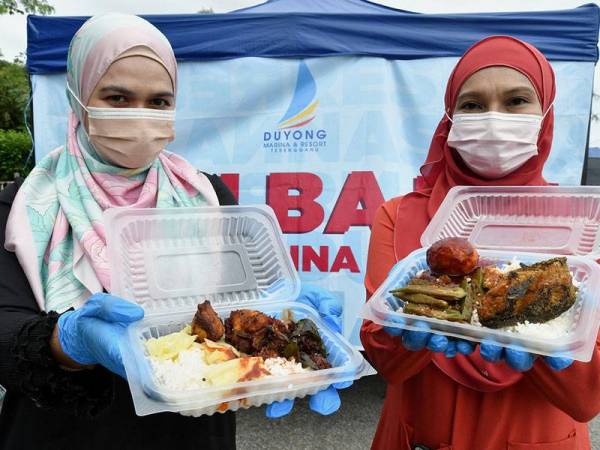 Kakitangan Duyung & Marina Resort (DMR), Tengku Irma Tengku Othman (kanan) dan Wahida Ghazali menunjukkan pilihan nasi bajet RM3 yang ditawarkan kepada pelanggan di gerai nasi bajet di Jambatan Sultan Mahmud, hari ini.