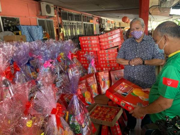 Annuar (kanan) bersama ketua penduduk melihat hamper Tahun Baharu Cina yang diberikan kepada penghuni yang diraikan pada Sabtu.