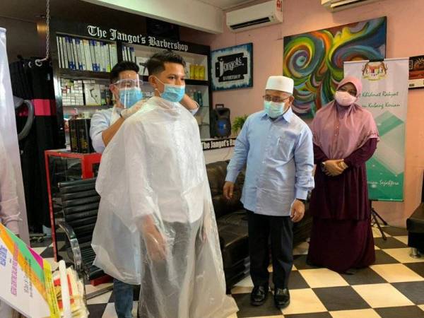 Tuan Ibrahim (dua,kanan) melihat pemakaian prosedur operasi standard (SOP) yang perlu diguna semasa proses gunting rambut.