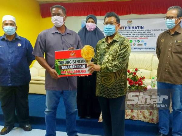 Che Abdullah (dua dari kanan) menyampaikan cek dari Tabung Bencana Tanaman Padi bernilai RM134,499.60 kepada wakil petani di PPK Rantau Panjang.