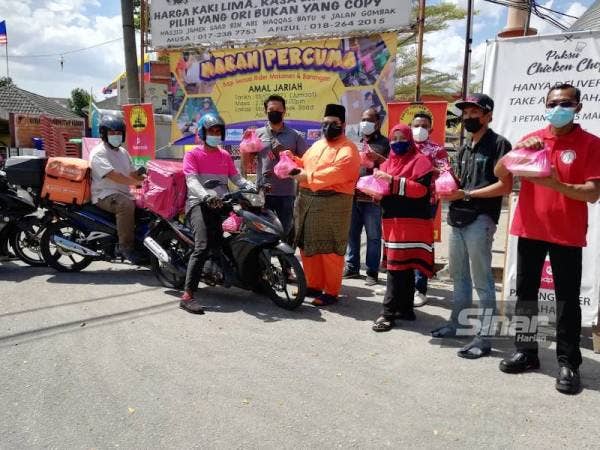 Penganjur mengagihkan bungkusan makanan kepada penghantar makanan dan barangan di pekaramgan Masjid Jamek Saad Bin Abi Waqqas