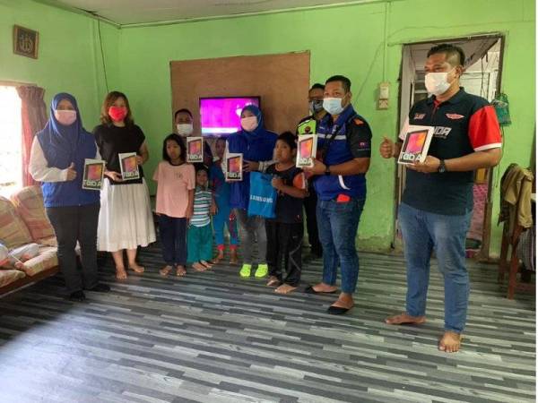 Nur Ain (tengah) menyerahkan sumbangan tab kepada keluarga Mohd Johan untuk digunakan tiga anaknya bagi mengikuti sesi PdPR di Kampung Seri Bahagia, Pasir Gudang pada Sabtu.