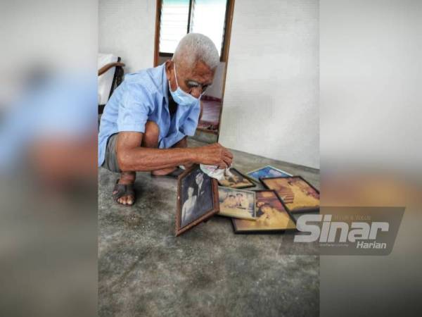 Lean Ngang membersihkan gambar lama keluarga mereka untuk digantung di dinding rumah.