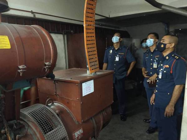 Khairil Adli (kiri) memeriksa sistem pemasangan tetap CO2 semasa pemeriksaan keselamatan kebakaran bangunan sempena Tahun Baharu Cina 2021 di Pasaraya The Store di Teluk Intan pada Isnin.