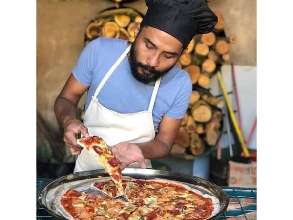 Che Ku Nasir di samping piza bersaiz XXXL yang dihasilkan menggunakan kaedah pembakaran tradisional. FOTO: Facebook Ulicafe