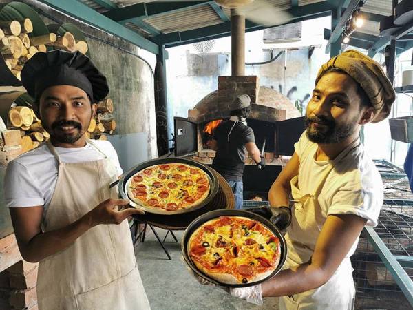 Che Ku Nasir (kanan) dan Che Ku Basir menunjukkan pizza yang dihasilkan menggunakan kaedah tradisional daripada bahan bakar kayu api dan tempurung serta ketuhar tanah liat.