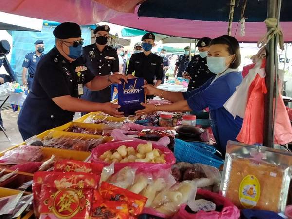 Azhar (Kiri) menyebarkan maklumat pematuhan SOP kepada peniaga Pasar Pagi Pekan Kulim pada Selasa.