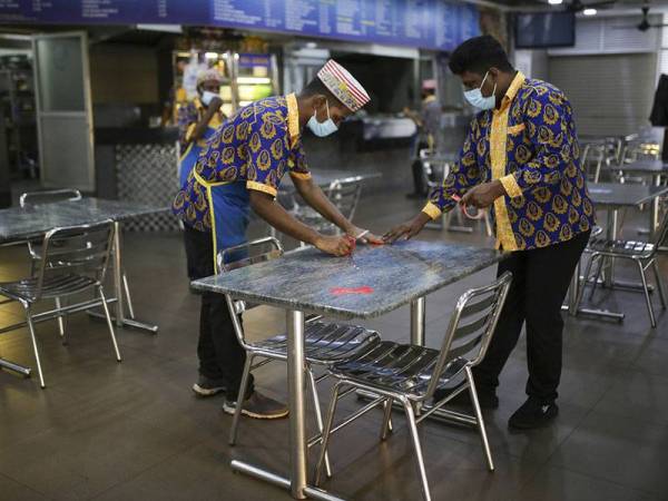 Pekerja sebuah restoran nasi kandar dilihat meletakkan penanda pada setiap meja yang hanya dihadkan untuk dua orang seperti disarankan oleh Kerajaan sebagai jarak sosial yang selamat ketika tinjauan di premis tersebut, hari ini. 